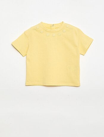 Camiseta lisa con flores de fantasía en el cuello