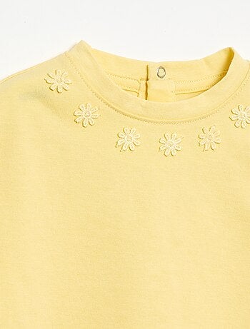 Camiseta lisa con flores de fantasía en el cuello