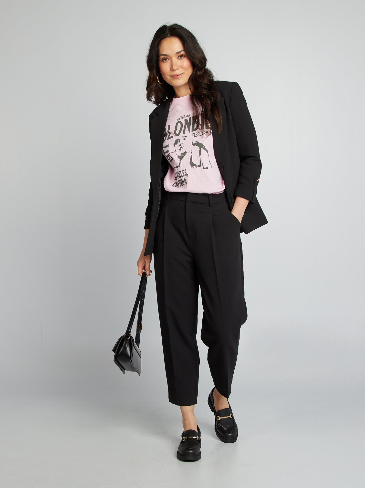Pink graphic T-shirt worn with an open black blazer, black tailored trousers and leather loafers